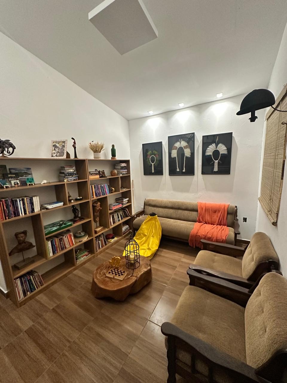 Sala de estar com biblioteca e quadros de cocares